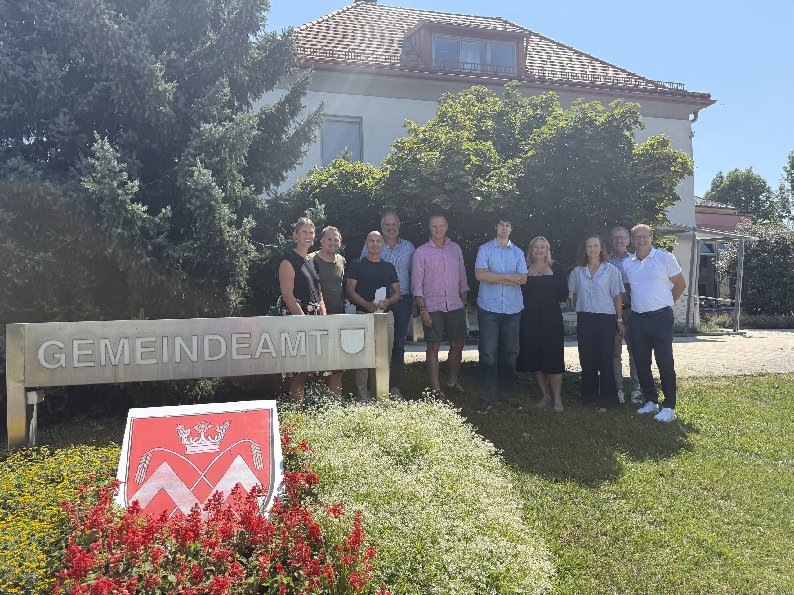 Gemeindeteam mit Gemeindewappen vor dem Gemeindeamt in Niederösterreich